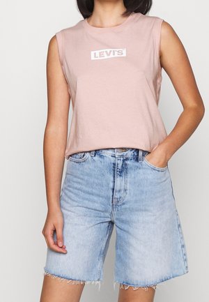 Roze mouwloos shirt met witte "LEVI'S" logo, gecombineerd met lichtblauwe denim shorts met franjes en een klassieke rechte pasvorm.