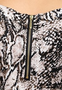 Tissu à imprimé serpent en nuances de brun et noir, présentant une fermeture éclair dorée proéminente au centre. Texture douce avec un détail de motif complexe.