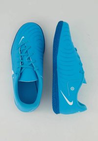 Zapatillas Nike azules con un upper liso, patrones texturizados, cordones planos y un logo blanco en contraste. La suela tiene un patrón de agarre texturizado.