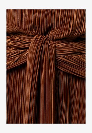 Tissu plissé métallique brun, rassemblé et noué au centre, créant des plis verticaux texturés et des reflets brillants.