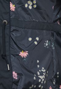 Marinblåt stof med spredte blomstermønstre med pink tusindfryd og hvide blomster. Glat tekstur med snoretræk.