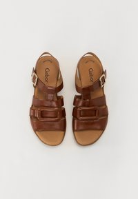Sandali in pelle marrone con più cinghie, una fibbia laterale e una soletta imbottita, caratterizzati da una texture liscia e un design con punta aperta.