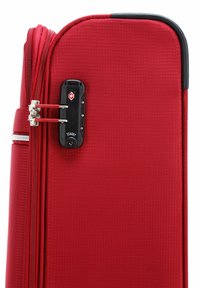 Valigia rigida rossa con finitura testurizzata, doppia cerniera e lucchetto a combinazione con logo rosso. Design compatto e rettangolare.