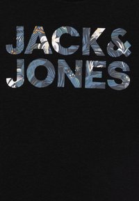 Černé tričko s nápisem "JACK & JONES" ve velkých vzorovaných písmenech s modrým a zeleným květinovým designem.