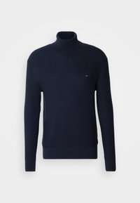 Pull à col roulé en maille gaufrée bleu marine avec manches longues et petit logo rouge, blanc et bleu sur la poitrine gauche.