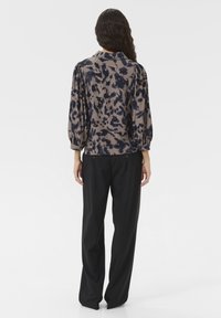 Bluză cu imprimeu leopard maro și marin, cu mâneci puff de 3/4, guler butonat și croială lejeră, asociată cu pantaloni negri.