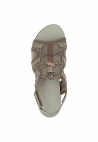 Sandale beige avec une tige en mesh et des sangles croisées, semelle intérieure rembourrée, et une bride de cheville ajustable. Semelle en caoutchouc lisse.