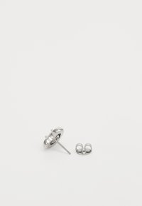Hõbedased studs-kõrvarõngad, millel on ümmargune, sile disain, tagumine post ja turvaline klamber selle kõrval.