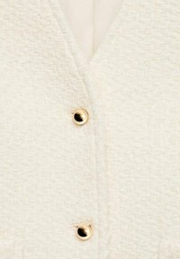 White textured cardigan with a woven pattern, featuring a v-neckline and two gold-tone buttons at the front. Soft fabric.