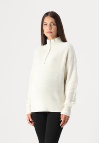 Bijela pletena veste s visokim ovratnikom i zatvaračem na pola. Sadrži rebraste manžete i rub; široka silueta s teksturiranom površinom.