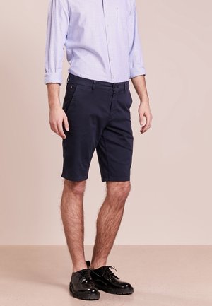 Navy cotton shorts with a tailored fit, featuring belt loops, side and back pockets, and a smooth texture. Worn with a blue striped shirt.