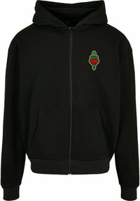 Svart hettegenser med glidelås, frontlomme, ribbestrikkede mansjetter, og et grønt og rødt broderi av et hjerte på brystet. Myk stofftekstur.