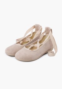 Ballerine in suede beige con una texture morbida, punta rotonda e cinturini regolabili. Nessun hardware visibile, design minimalista.