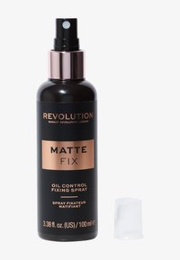 Flacone di spray fissante opacizzante Revolution Matte Fix con controllo dell'olio, design nero e oro rosa, ugello spray e cappuccio in plastica trasparente accanto.