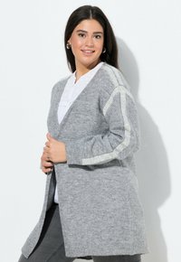 Grå stickad cardigan med V-ringning och långa ärmar. Har kontrasterande randiga detaljer på axlarna. Mjuk textur och öppen framdesign.