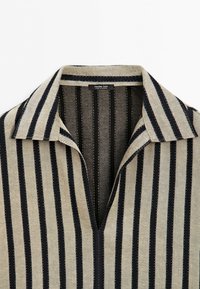 Beige and black vertically striped collared shirt with open neckline and visible brand label inside collar.
