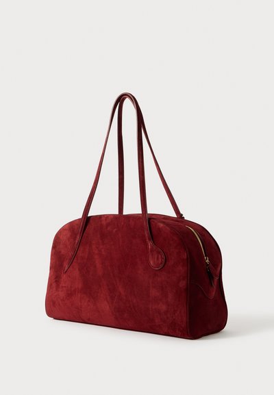 Borsa da viaggio in suede rosso con due manici lunghi, forma arrotondata e una cerniera laterale. Texture liscia con cuciture e dettagli sottili.