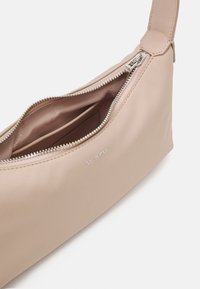 Borsa a spalla in pelle marrone chiaro con chiusura a zip, texture liscia e tasca interna. Presenta logo impresso e una tracolla ampia e regolabile.