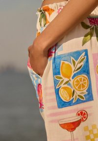 Shorts i blommönstrad tyg med en färgglad citrusdesign i rosa, gult och blått. Inkluderar en sidoficka för bekvämlighet.