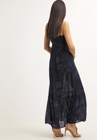 Maxime dress i mörkblått tyg med en åtsittande bodice och en flödande, lager-på-lager kjol, med subtila blommönster och spaghetti band.