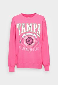 Różowa bluza z długim rękawem, z nadrukiem "TAMPA" i "CLEARWATER BEACH" w białym i złotym kolorze. Okrągły dekolt. Wykonana z miękkiego materiału.