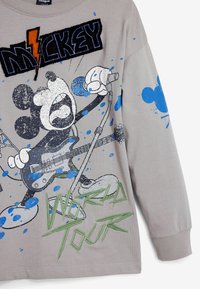Harmaa pitkähihainen t-paita, jossa on värikäs graafinen kuva sarjakuvahahmosta kitaran kanssa, tekstit "MICKEY" ja "WORLD TOUR", sinisen ja vihreän sävyin.