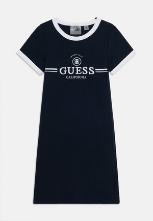 Marineblaues Kleid mit kurzen Ärmeln, weißen Kragen und Manschetten, mit dem "Guess California Sports Club" Logo auf der Brust.