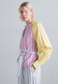 Striped shirt with pastel colors: lavender and yellow with blue accents. Features a tie waist and puffed sleeves. Smooth texture.