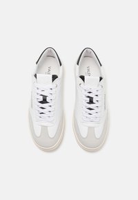 Hvite lær sneakers med grå semsket skinn detaljer og svarte elementer. Har flate lisser, rund tå, og et minimalistisk design.