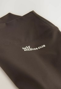 Mustad mustad spordilegendi, mis on valmistatud venivast kangast sujuva tekstuuriga. Omab valget "self. ATHLETICS CLUB" logo ja lamedaid õmbluseid.