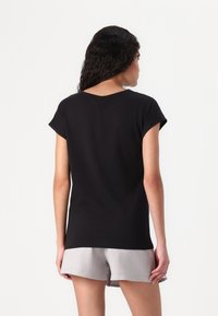 Black short-sleeve t-shirt with a round neckline, made of soft material. The back features a subtle seam detailing and a relaxed fit.