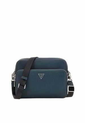 Sac bandoulière compact bleu foncé avec compartiments zippés et sangle noire ajustable, avec un petit logo métallique de la marque à l'avant.