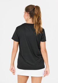 Sort kortærmet sportstop, lavet af fugttransporterende materiale, glat tekstur, afslappet pasform, med rund halsudskæring og blød kant.