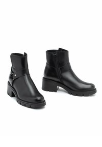 Czarne skórzane botki na kostkę o gładkim wykończeniu, z szerokim obcasem, bocznym zamkiem błyskawicznym oraz ozdobnym paskiem z srebrnymi akcentami. Płaska podeszwa z przyczepnością.