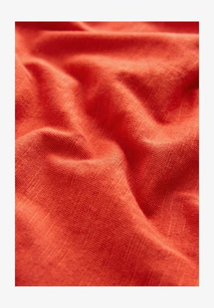 Oranžs audums ar teksturētu, mīkstu austu izskatu. Virsma rāda smalkas variācijas un krociņas, kas norāda uz vieglu materiālu.