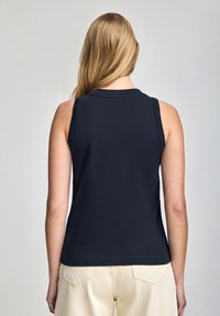 Granatowy top bez rękawów wykonany z bawełny, z okrągłym dekoltem i prostym krojem. Gładka tekstura bez widocznych wzorów czy akcentów.