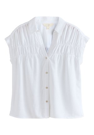 Blouse blanche à manches courtes avec boutons et col, détails froncés sur le plastron au niveau de la poitrine et tissu léger.