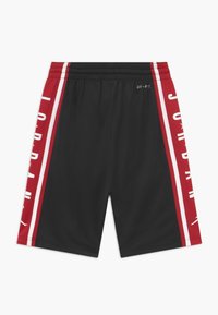 Black athletic shorts featuring red side panels with white stripes and "JORDAN" text. Made from moisture-wicking fabric, elastic waistband.