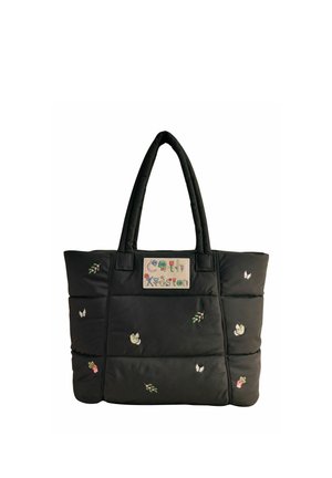 Sac cabas matelassé noir avec poignées rembourrées, petites fleurs et papillons brodés, et patch de marque rectangulaire coloré sur le devant.