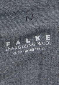 Šedá vlnená ponožka s ribbovanou štruktúrou, na povrchu s bielou potlačou značky "FALKE ENERGIZING WOOL" a informáciami o veľkosti.