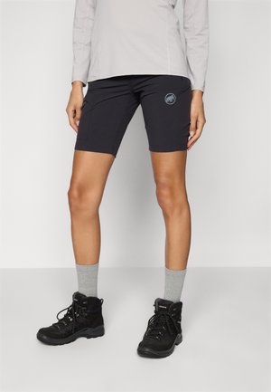Pantaloni corti neri con tasche cargo, abbinati a calzini grigi e stivali da escursionismo neri. I pantaloni corti presentano un piccolo logo di lato.