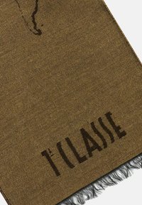 Sciarpa di tessuto marrone con bordo sfrangiato, con testo marrone scuro "T'CLASSIE" ben visibile. Superficie texturizzata con motivo sottile.