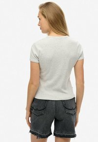 Grå T-shirt med korte ærmer og tætsiddende design, parret med højtaljede sorte denim shorts med frynset kant og dekorative stikninger.
