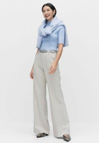 Jasnoniebieski, prążkowany top zestawiony z kremowymi spodniami w szerokich nogawkach. Dopasowany jasnoniebieski szalik opada na ramionach. Buty w wężowy wzór dopełniają całość.