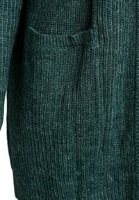 Tissu de pull en maille vert foncé avec une texture côtelée verticale visible et une petite poche à l'avant.