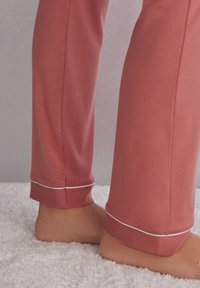 Lichtroze katoenen loungebroek met een slim fit, voorzien van een geribbelde zoom en witte accentstiksels bij de enkels. Zachte textuur, geen patronen.