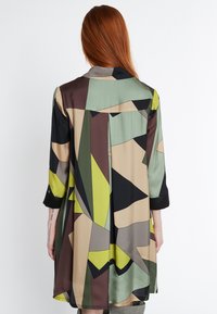 Satin-Kleid mit geometrischem Muster in Grün, Schwarz, Braun und Beige. Es hat einen Kragen und Dreiviertelärmel.