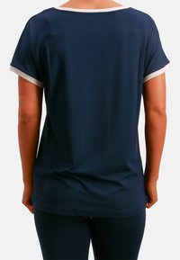 Marineblaues Kurzarmoberteil mit weißem Besatz entlang des Halsausschnitts und der Ärmel. Glatter Stoff, lockere Passform und abgerundeter Saum.
