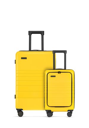Yellow hard-shell luggage set with black accents; features a ribbed design and retractable handles. Includes a large suitcase and a smaller carry-on.