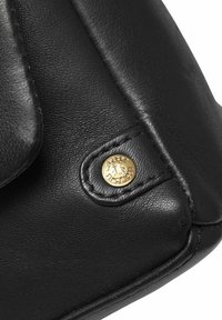 Čierna kožená kabelka s rohom, ktorý sa vyznačuje zlatým kruhovým logom, textúrovaným povrchom a viditeľným štepovaním.